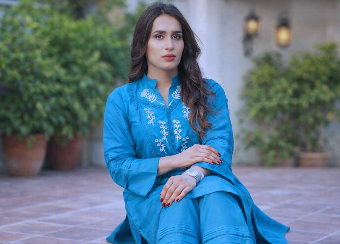 Celebrity sitting outdoors in blue traditional wear
