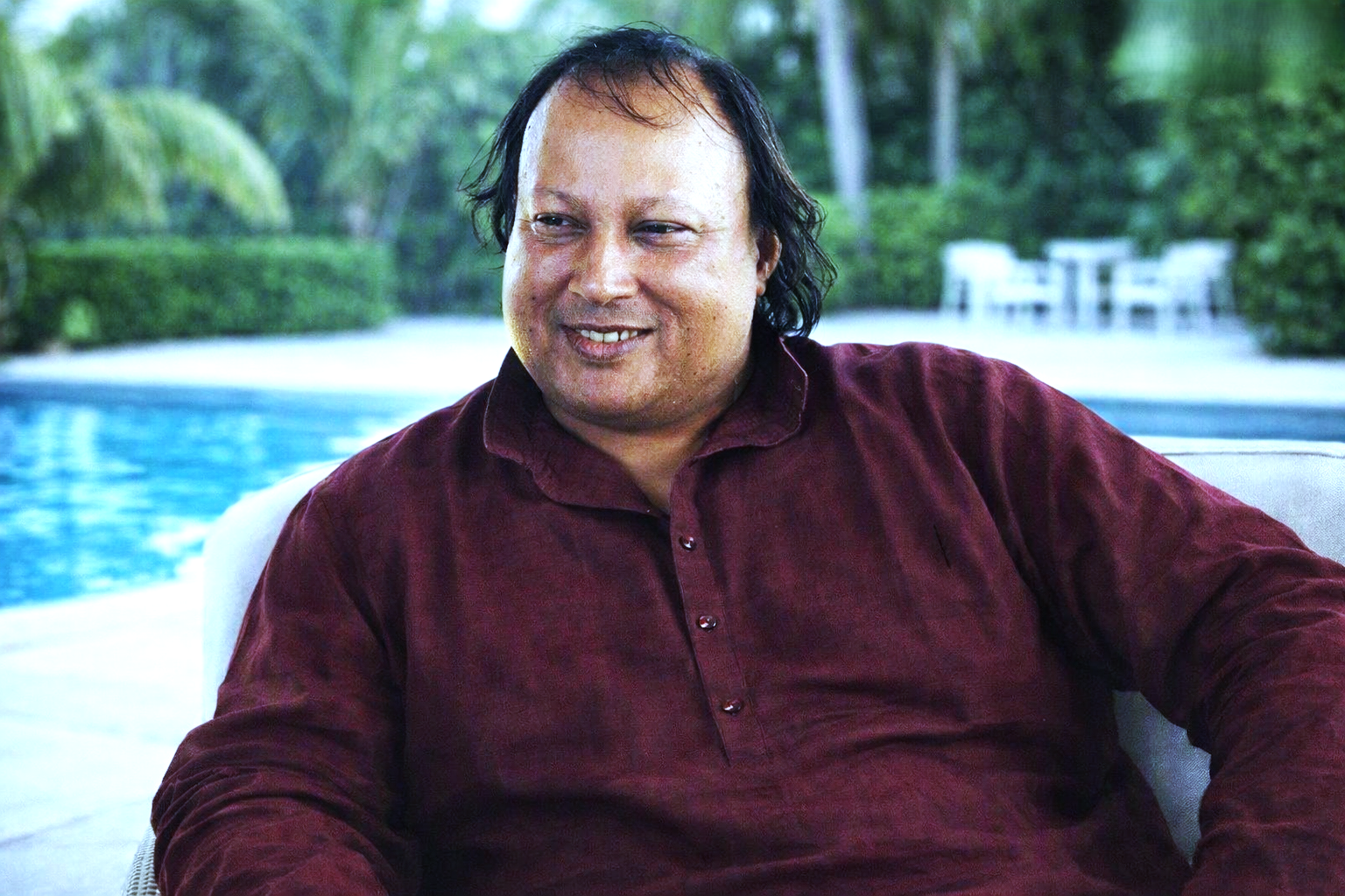 Maroon shirt mein muskuraate hue singer swimming pool ke paas.