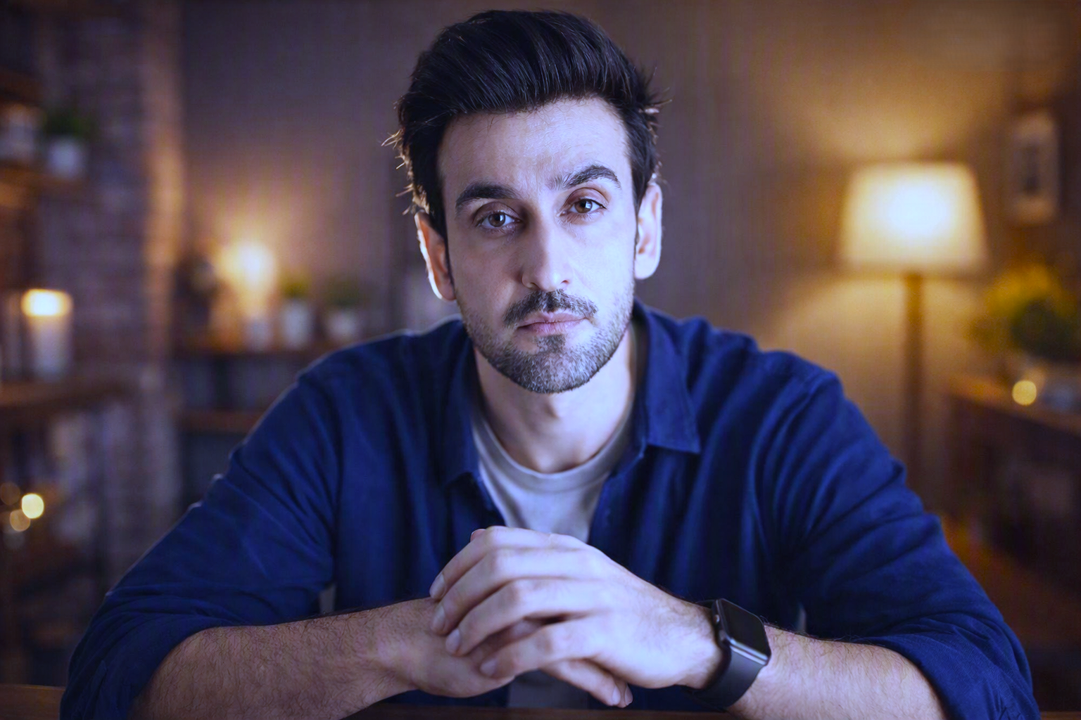 Blue open shirt mein larka hath jore baitha hai