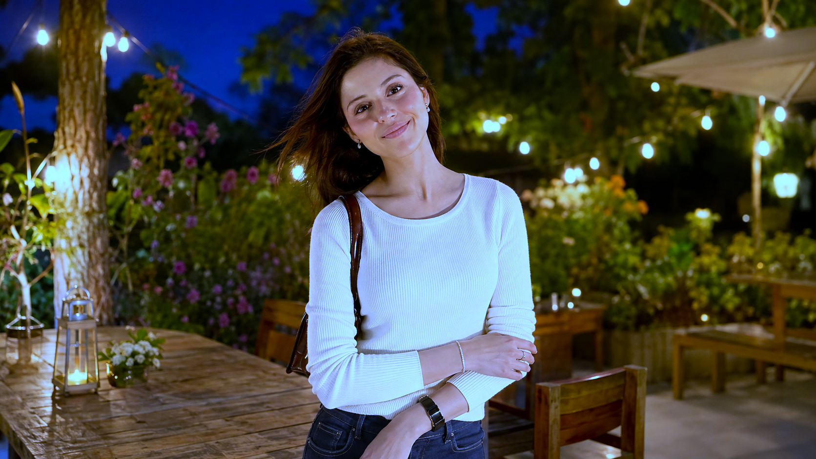 White top aur jeans mein smiling fashion model outdoor garden setting mein