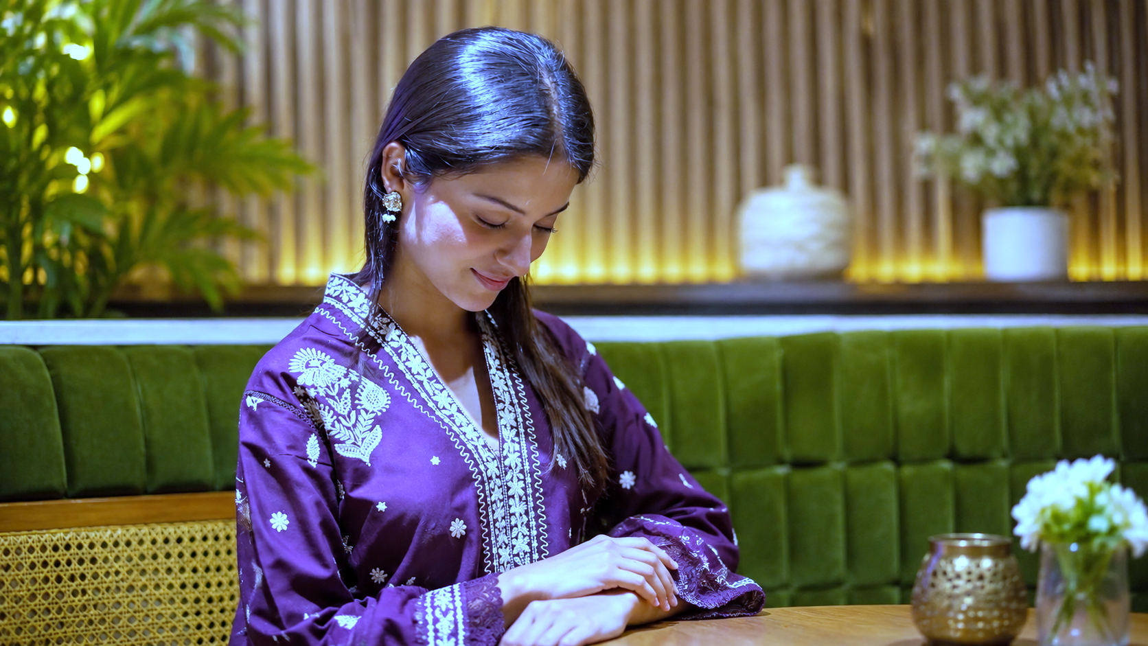 Decorated purple kurta mein desk par baithi hui fashion model