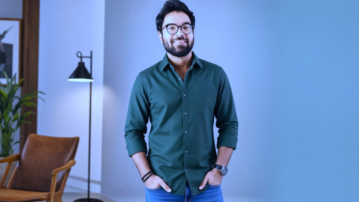 Celebrity green formal shirt aur glasses mein pose karte hue